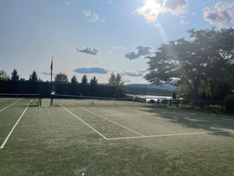 The sun low over the Twin Lakes courts, with the lake shining past the far fence