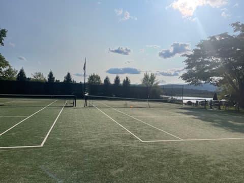 Late afternoon sun over the courts at Twin Lakes Beach Club, the lake and hills beyond the fence
